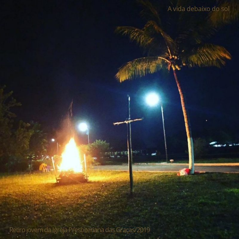 A imagem mostra uma fogueira, uma cruz feita de bambu e um coqueiro. Foto tirada no retiro de jovens da Igreja Presbiteriana das Graças, 2019. O tema foi a vida debaixo do sol, baseado em Eclesiastes.